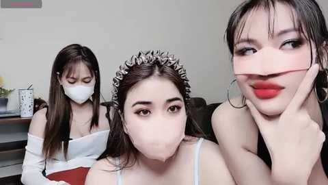 Media: A video featuring three Asian women in a living room: one wearing a white mask, another with a white headband, and a third with red lipstick, all smiling.