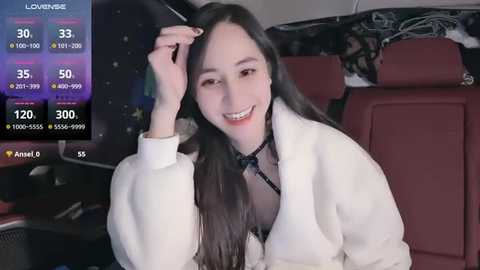 Media: A video of a smiling, long-haired East Asian woman in a white fur coat, seated in a car with a purple dashboard.