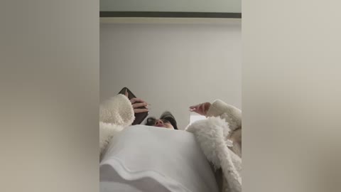 Media: Video of a person in a white fluffy robe, capturing their reflection in a mirror, with a minimalist, neutral-toned background.