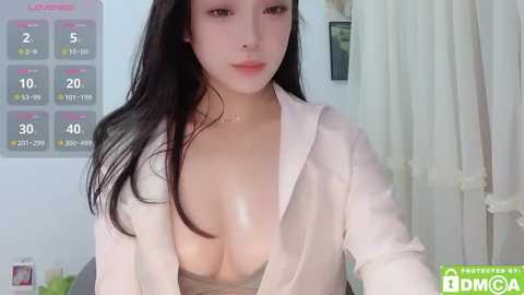 Media: Video of a young Asian woman with long black hair, fair skin, wearing a low-cut white shirt revealing her ample cleavage. Background includes a white curtain and a calendar showing the days of the week.