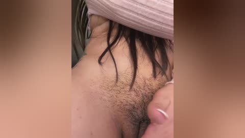 Media: Video of a close-up of a woman's pubic region with dark, natural hair, partially covered by a pink shirt, showing light skin and a few blemishes.