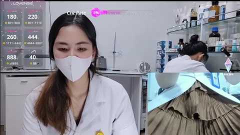 Video of an Asian woman in a white lab coat and mask, standing in a lab with a digital screen displaying COVID-19 data. Background shows a scientist in a hazmat suit working at a lab bench.