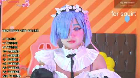 Media: A vibrant, digitally edited video features a young woman with blue hair in a maid costume, seated in a colorful, orange-striped room. She wears a frilly white dress and a black bow.