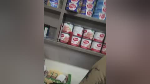 Video of a grocery aisle with shelves stocked with Campbell's Soup cans, including red and white labels. Background features a colorful poster of a farm scene.