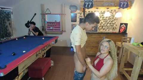 Media: A video captures a young man in a pool hall, shirtless with jeans down, approached by a blonde woman in a red top and braids, while a bartender observes.