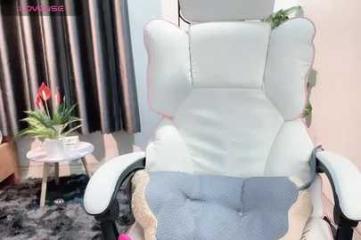 Media: Video of a plush white gaming chair with a textured blue blanket, set in a cozy room with dark curtains, a potted plant, and a small round table.