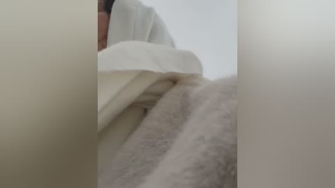 Media: A video showing a close-up of a person's face and neck, partially covered by a white cloth, with a blurred background.