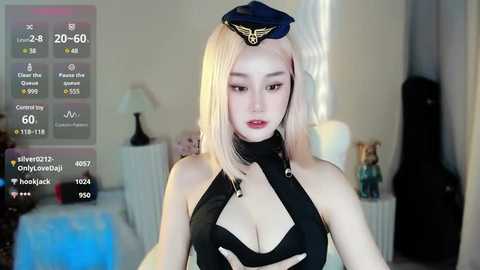 Media: Video of a young, light-skinned, blonde woman wearing a revealing black pilot costume with a hat, in a dimly lit bedroom.