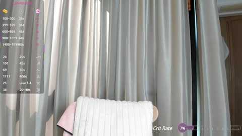 Video of a modern bedroom with sheer, light grey curtains, a white pillow, and a pink throw blanket on a white bed. The room features a wooden door and a purple Crate & Barrel logo in the bottom right corner.