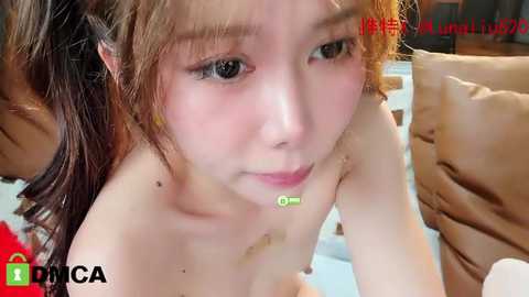 Media: Video of a young Asian woman with fair skin, wet hair, and a green surgical mask, lying on a bed, with visible bruises on her neck. Text in red and green overlaid.