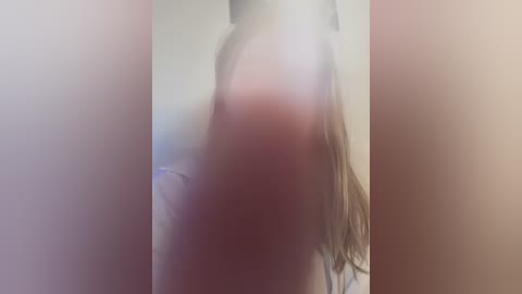 Media: A blurred video of a woman with long, straight brown hair, partially visible due to the hazy, washed-out filter. The background is indistinct, possibly indoors with neutral tones.