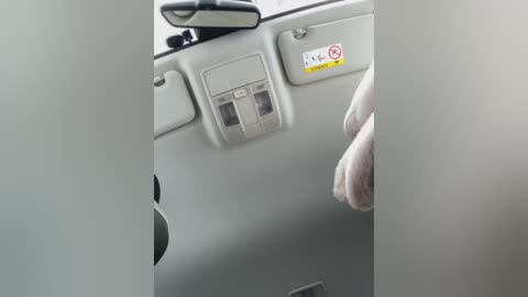 Media: Video of a vehicle's interior, showing a beige dashboard with a small, transparent compartment for a toll card, a mirror, and a visible hand.