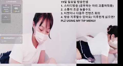 Media: Video of a young Asian woman in a white mask and glasses, wearing a white t-shirt, lying on a bed, with Korean text on screen.