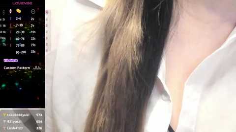 Media: Video of a woman's long, straight brown hair partially covered by a white blouse. The background features a smartphone screen displaying a color grading app interface.