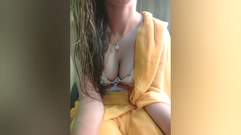 Media: Video of a woman with wet hair, wearing a yellow towel and a revealing, lace bralette with visible cleavage, indoors.