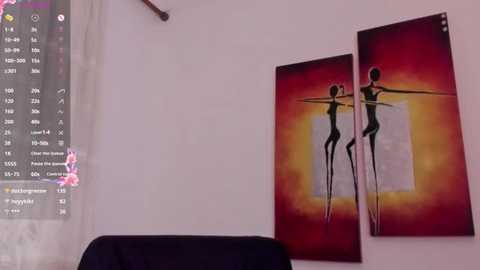 Media: Video of a minimalist bedroom featuring a black armchair, a white wall, and two abstract art pieces depicting silhouetted dancers in red and orange hues.