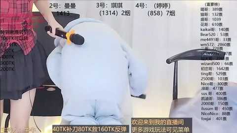 Media: A video shows a person in a furry suit resembling a bear with a blue and white coat, being groomed with a brush by another person. The background features a black chair and a wall with Chinese text.