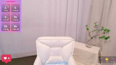 A video of a white, plush armchair with a blue cushion in a minimalist, white room with a purple digital menu on the left, a potted plant on a table to the right.