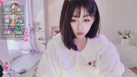 A video of a young Asian woman with straight, shoulder-length dark hair, wearing a white blouse, in a pastel-themed room with floral decor, virtual reality display overlaying her face.