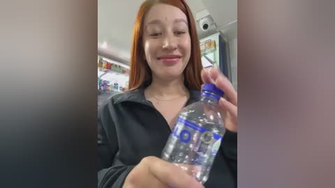 Media: Video of a young Asian woman with straight, auburn hair, wearing a black jacket, holding a clear water bottle in a supermarket. Background shows shelves and a refrigerator.