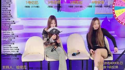 Video of two young women with long hair, one in a black turtleneck and denim shorts, the other in a gray hoodie and jeans, sitting on white chairs in a brightly lit studio, surrounded by Chinese text and images.