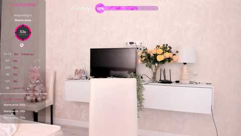 A video of a modern, minimalist living room with a white TV on a white floating shelf, a vase of yellow roses, and a white lamp.