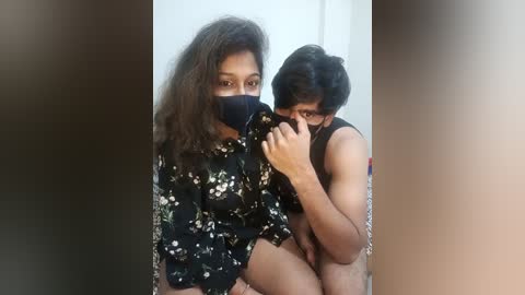 Media: Video of two young South Asian men, one with a floral shirt and face mask, the other shirtless, kissing passionately in a dimly lit room.