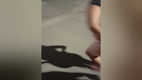 Media: A blurred video captures a person's silhouette, wearing a black t-shirt, running on a concrete floor. The background features a dark, indistinct figure in the shadows. The image is grainy and slightly out of focus.