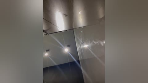 Media: Video of a modern, minimalist ceiling featuring reflective surfaces and recessed lighting, creating a sleek and clean aesthetic. The image captures the geometric lines and smooth textures of the ceiling, emphasizing a contemporary interior design style.