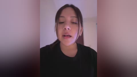 Media: Video of a young Asian woman with light skin, straight dark hair, and closed eyes, wearing a black shirt, against a blurred background.