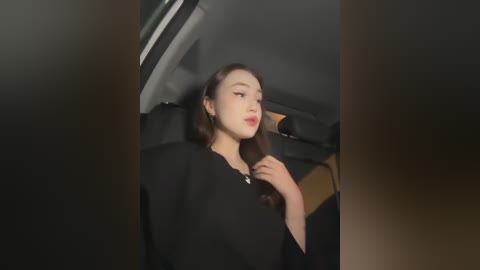 Media: A video of a young woman with long brown hair, wearing a black top, sitting in the backseat of a car, looking out the window.