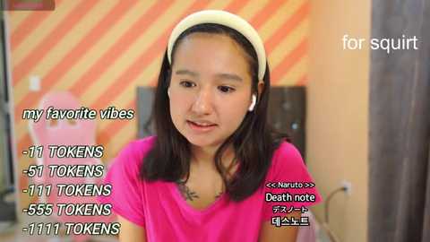 Media: A video of a young Asian woman with long black hair, wearing headphones, a pink t-shirt, and a white headband. Text overlays mention \"my favorite vibes,\" \"51 tokens,\" \"Death note,\" and \"1151 tokens.\