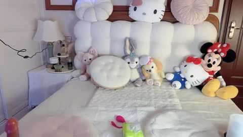 Media: A video of a whimsical, white-themed bedroom featuring plush Hello Kitty and Disney characters on a neatly made bed, with soft lighting and a cozy atmosphere.