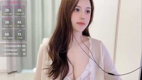 Media: Video of a young East Asian woman with long brown hair, fair skin, wearing a sheer white robe, and a white lace bra, with a digital overlay showing weather and social media notifications.