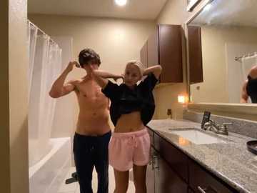 Media: Video of two shirtless men in a bathroom; one wearing a pink towel, the other adjusting his hair.