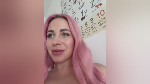 Media: A video of a fair-skinned woman with long, pastel pink hair, wearing makeup, looking at a large, blurry pink object. Background features a colorful wall chart with numbers and animals.