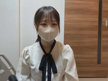 Media: Video of an Asian woman in a white blouse with puffed sleeves, black bow tie, and a white mask, standing in a modern, wooden-paneled room.