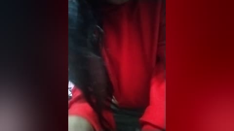 Media: Video of a person wearing a red sweater, blurred background, with a focus on their hands resting on their chest, creating a soft, intimate ambiance.