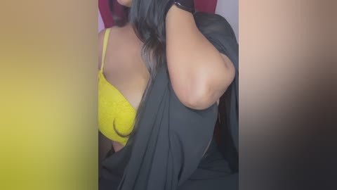 A close-up video of a woman with long, dark hair, wearing a bright yellow bra and a black jacket, partially unzipped.