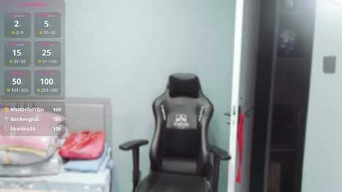 Media: A video of a modern gaming chair with a black and red design, positioned in a bright, minimalist room with a green wall and a partially open door. A digital display in the background shows various gaming statistics.