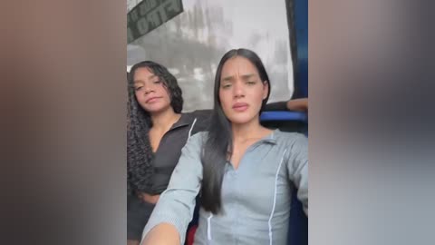 Media: Video of two young women with medium skin tones and long dark hair, smiling, wearing casual outfits, standing on a street corner.