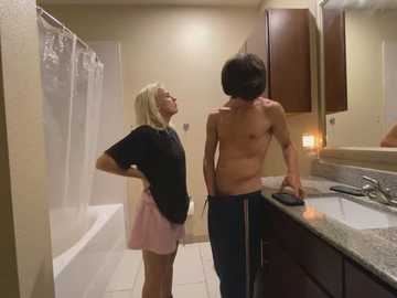 Media: Video of a blonde woman in a pink skirt and black shirt facing a shirtless man with short hair in a bathroom with a granite countertop.