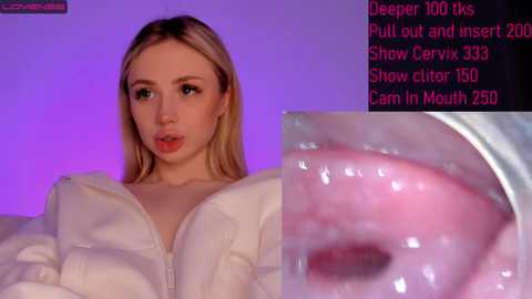 Media: Video of a young, fair-skinned, blonde woman with large breasts in a white top. Background features a purple gradient. Text overlay shows camera stats, including \"Show cam in Mouth 250.\" Close-up of her mouth with a pink tongue visible.