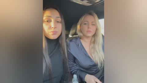 Media: Video of two young women, one with long dark hair, the other with long blonde hair, sitting side by side in a car. They wear black, low-cut, long-sleeve tops, giving a casual, relaxed vibe.