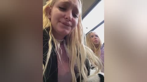 Media: Video of two young women with wet, long blonde hair, wearing casual clothing, smiling in a bus.