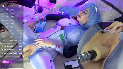 Media: A live stream screenshot of a person in a blue cosplay, reclining on a couch, with a visible sex toy and a smartphone in the foreground.