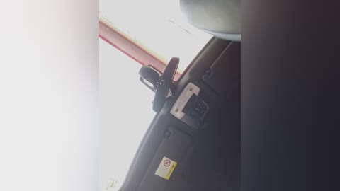 Media: Video of a car interior focusing on the dashboard with a red ignition key, a black and white hazard light switch, and a warning label. The background is a bright, white light source, possibly sunlight.