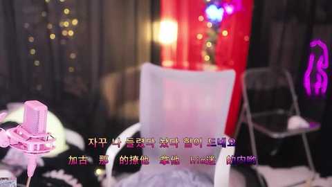 Media: Video of a dimly lit room with a white chair, a pink bow, a silver chair, a red curtain, and Korean text overlay.