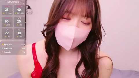 Media: Video of a young Asian woman with long brown hair and fair skin wearing a red bra and white surgical mask, set against a white background.