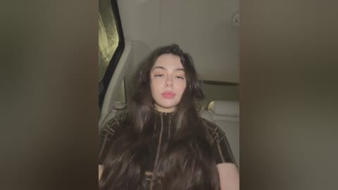 Media: Video of a young woman with long, dark hair, wearing a black leather jacket, sitting in a car, looking slightly to the right.